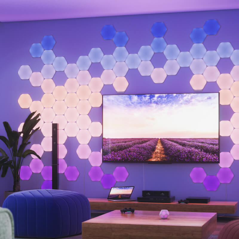 Nanoleaf Shapes Thread enabled color changing hexagon smart modular light panels mounted to a wall in a living room. Similar to Philips Hue, Lifx. HomeKit, Google Assistant, Amazon Alexa, IFTTT.